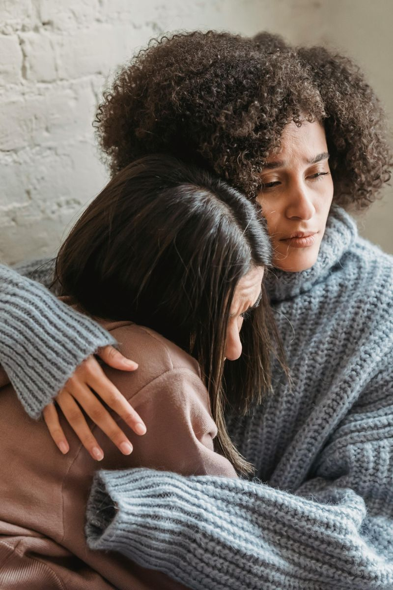 Two women embracing in a moment of emotional support and comfort, representing compassion, mental health awareness, and human connection